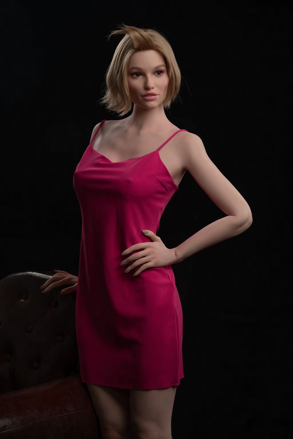 Секс-лялька Masha фото 6 - SexDolls.com.ua Секс лялька Masha в рожевій сукні стоїть біля коричневого крісла