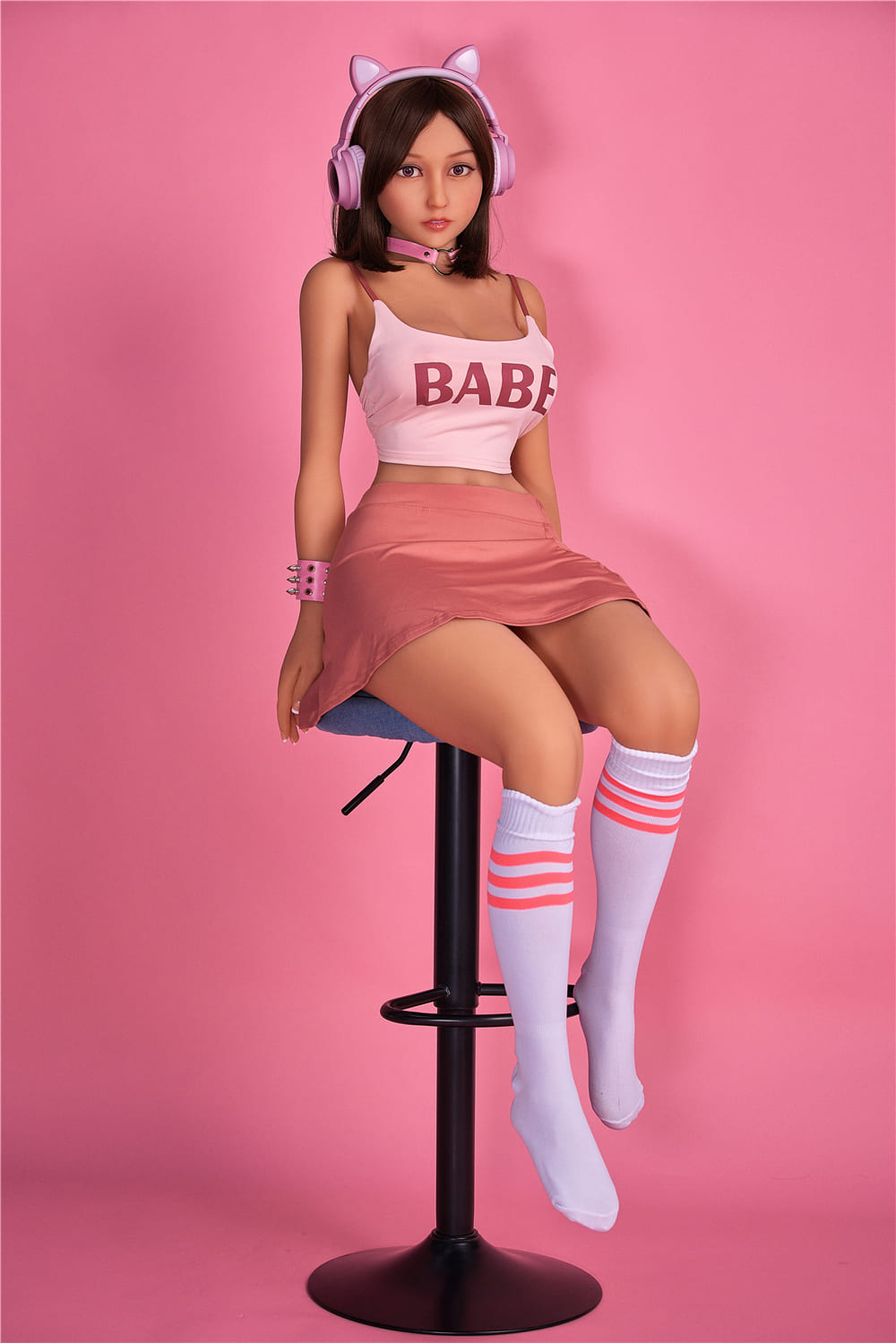 секс-лялька Marion - фото 8 - SexDolls.com.ua Секс лялька Маріон сидить на стільці на рожевий фон